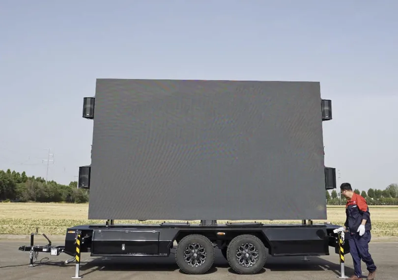 Crew standing beside a deployed MOBO MB-15 LED screen trailer for scale