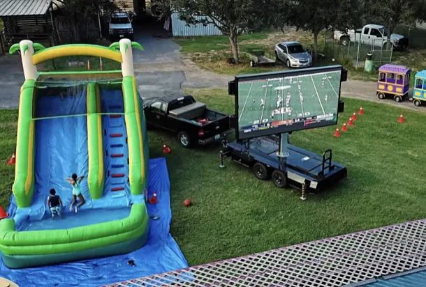 MOBO LED trailer showing a football game at a backyard tailgate with an inflatable slide