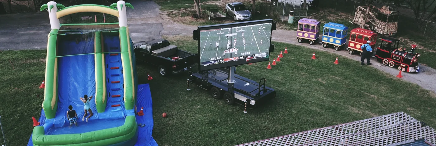 Aerial view of a MOBO MB-10 LED screen trailer showing football beside an inflatable slide